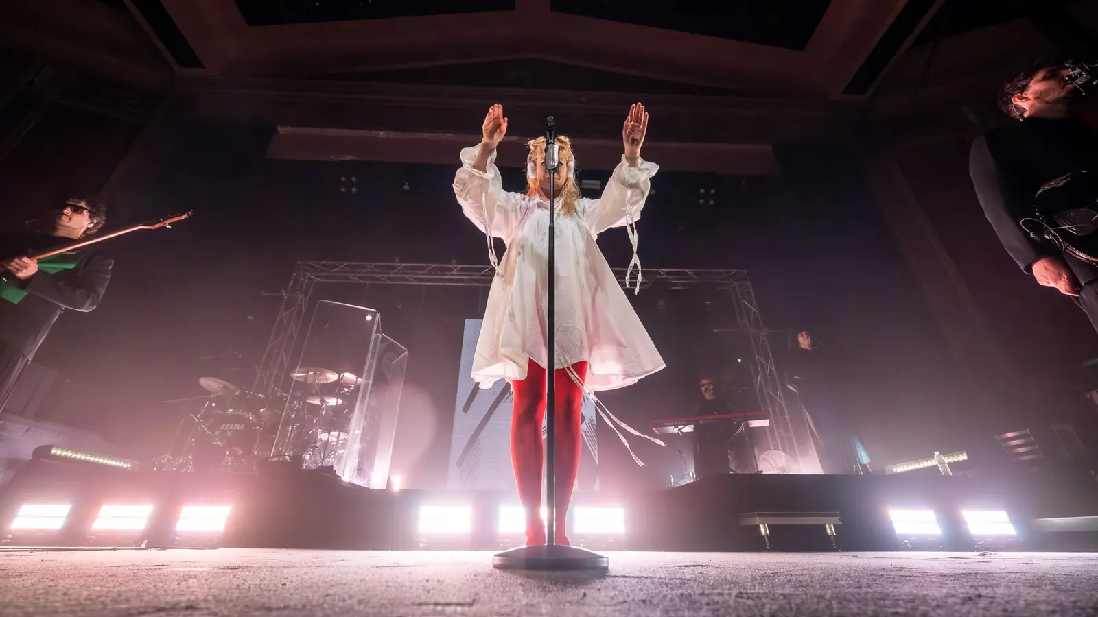 Singer facing the crowd beneath white stage lights