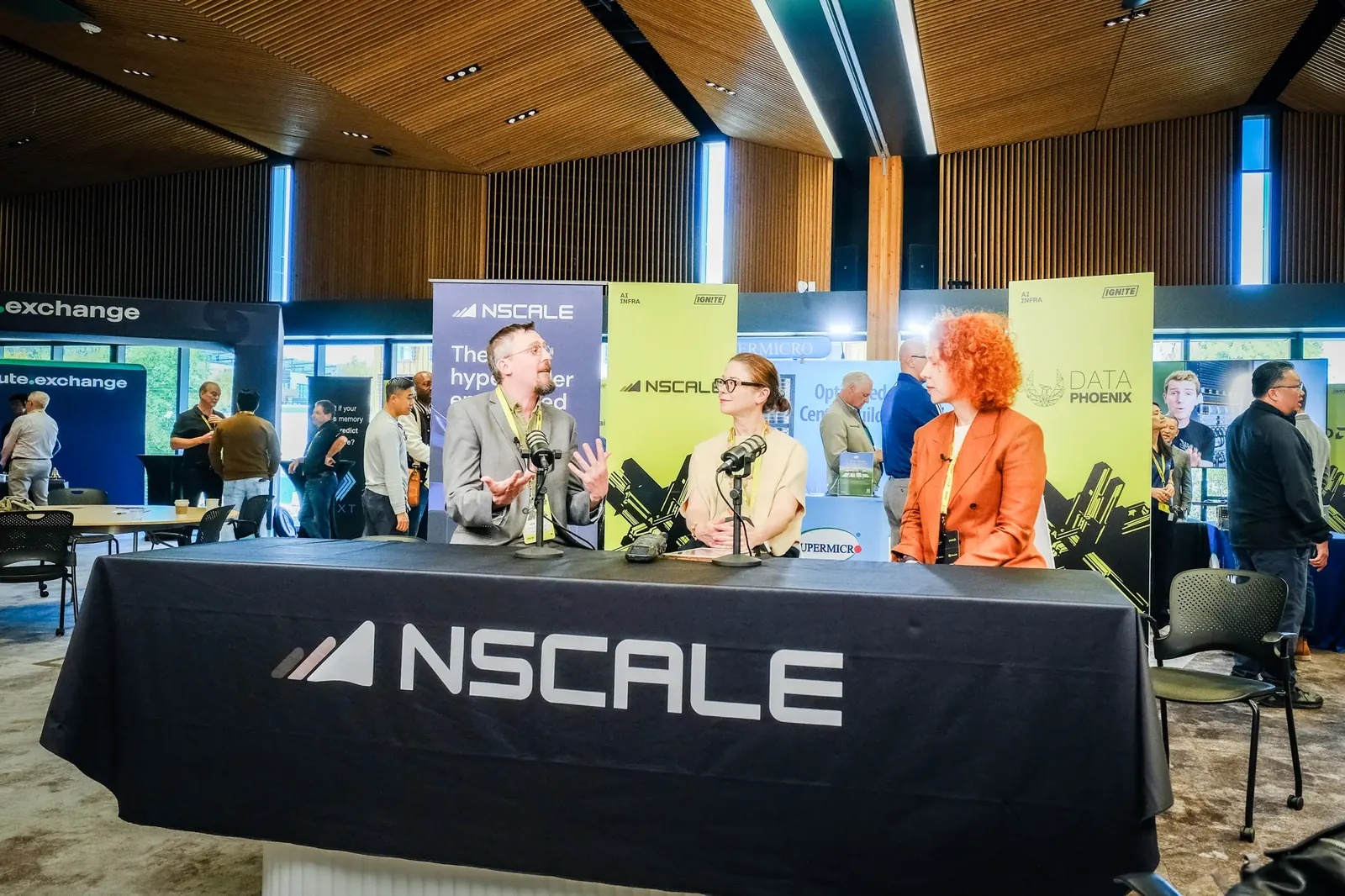 Three guests speaking at a branded interview desk inside an event
